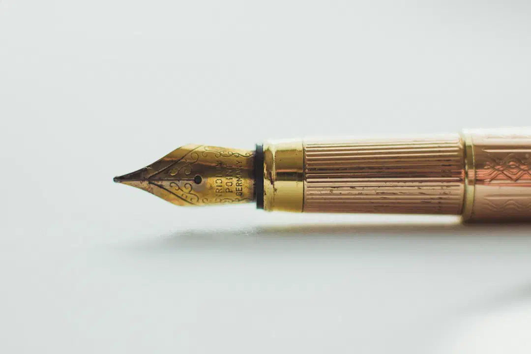 Close-up of a gold fountain pen nib on a white surface