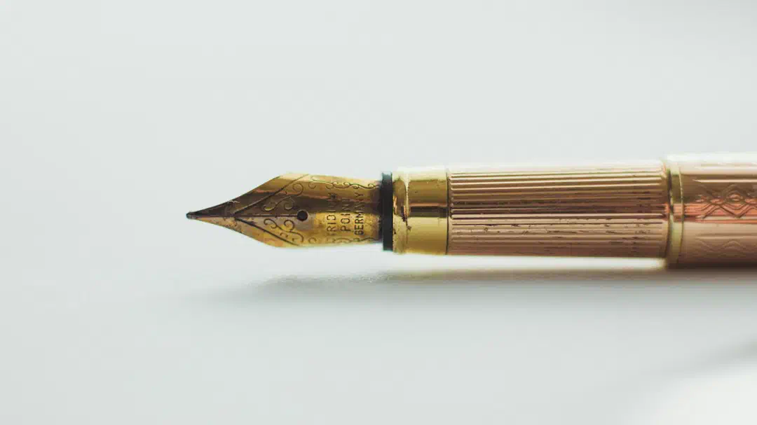Close-up of a gold fountain pen nib on a white surface