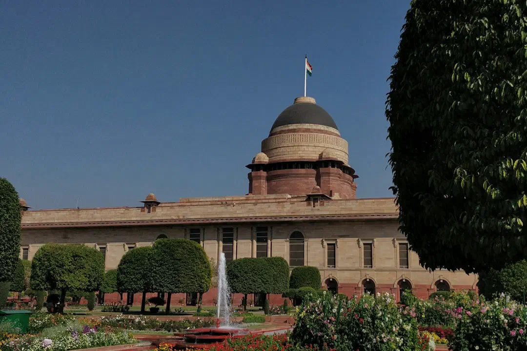 Rashtrapati Bhavan in New Delhi behind trees and a garden fountain
