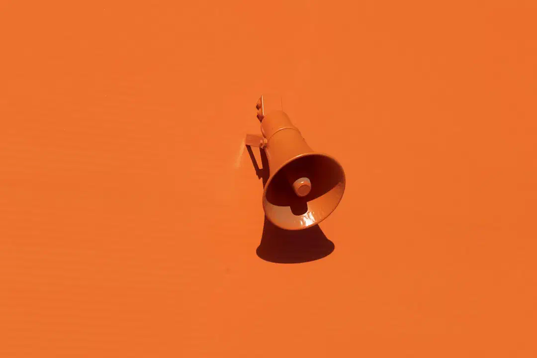 An orange megaphone mounted on an orange wall