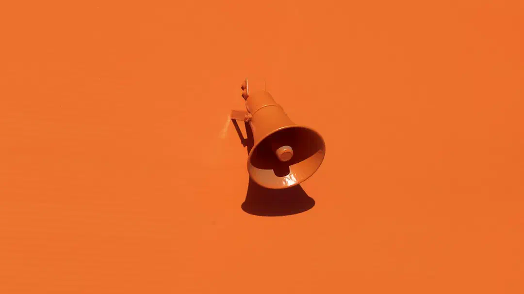 An orange megaphone mounted on an orange wall