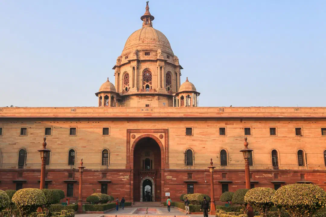 A domed sandstone Secretariat building in New Delhi under a clear blue sky