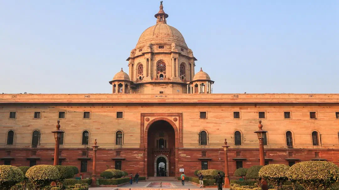 A domed sandstone Secretariat building in New Delhi under a clear blue sky