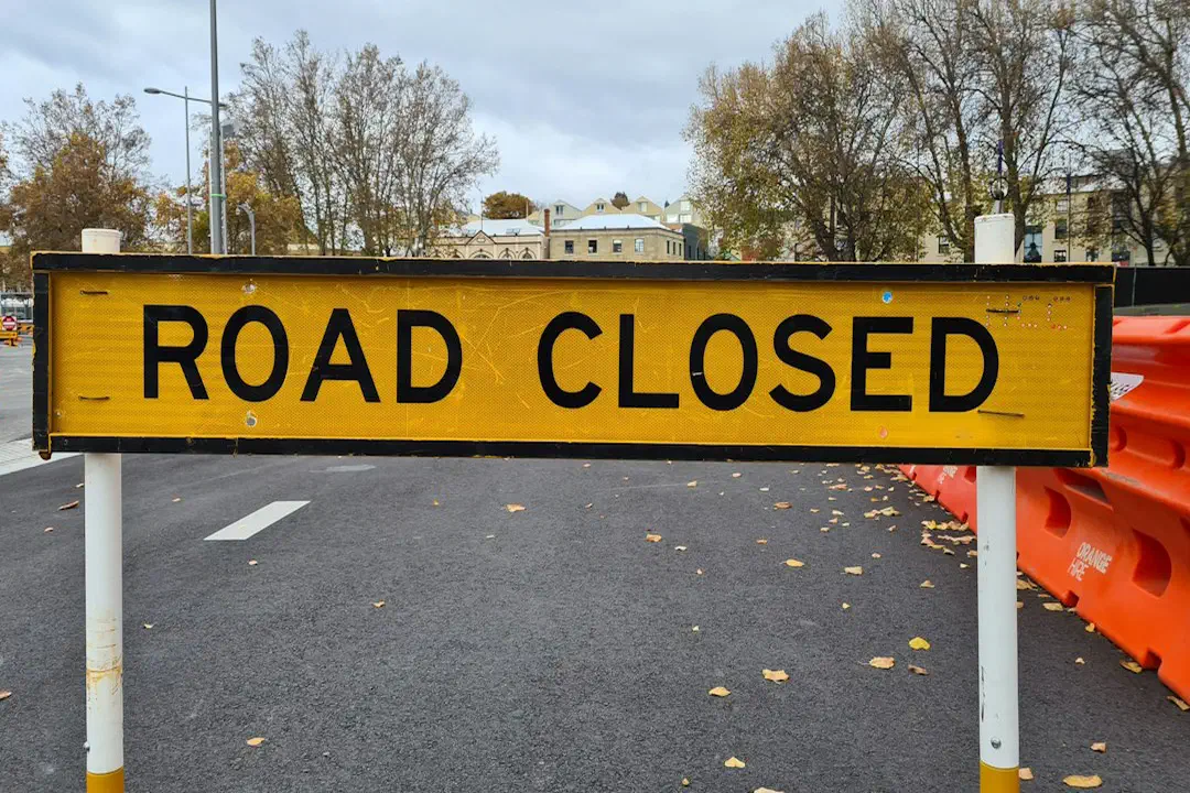 A yellow road-closed sign standing at the side of a road