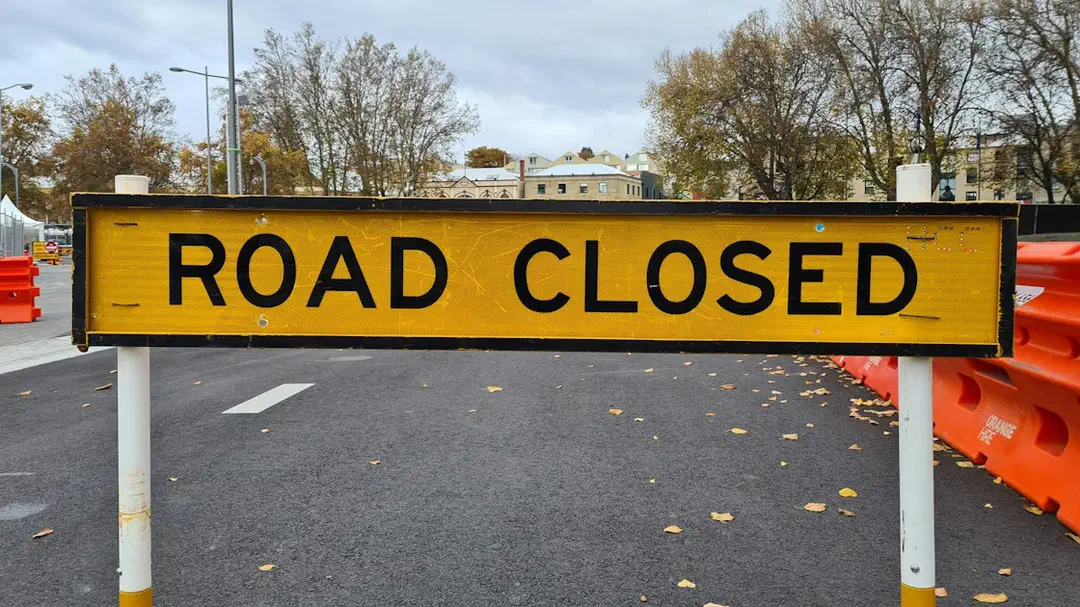 A yellow road-closed sign standing at the side of a road