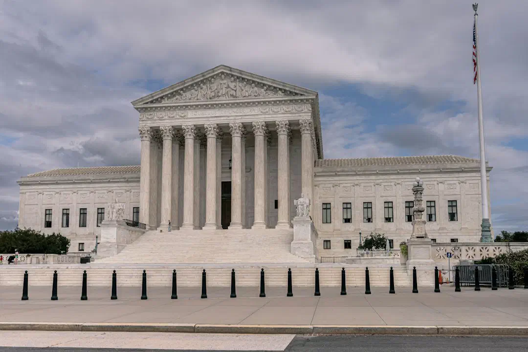 A white building with a portico under a cloudy sky