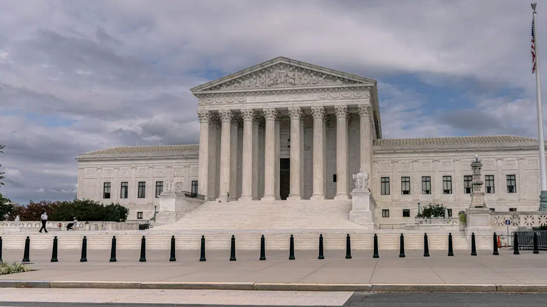 A white building with a portico under a cloudy sky