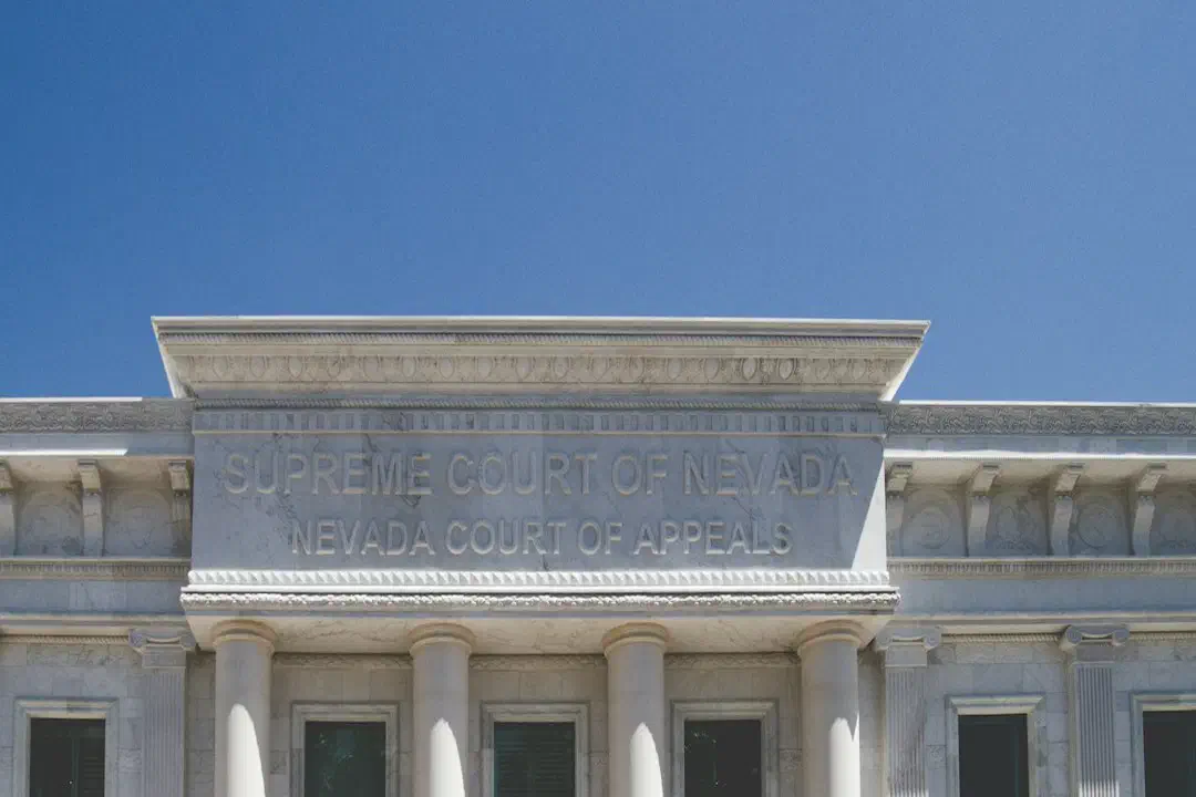 A white concrete building with columns under a cloudy sky