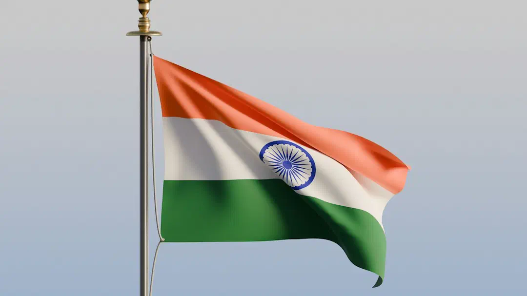 The national flag of India waving on a metal pole against a clear sky