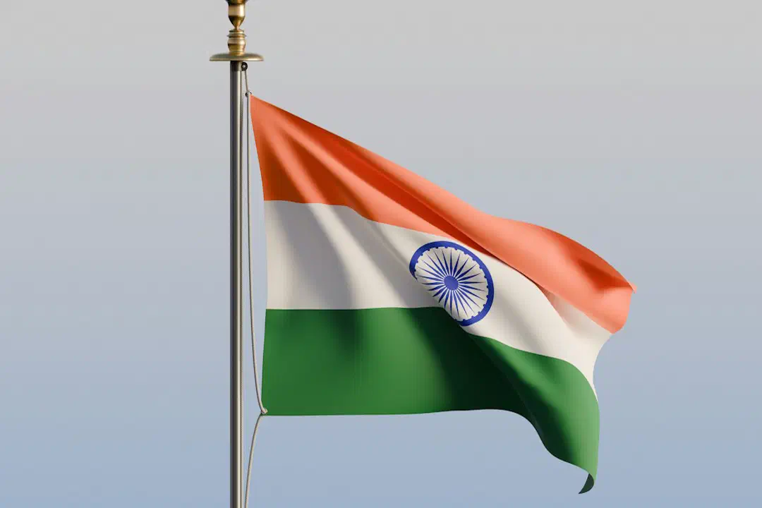 The national flag of India waving on a metal pole against a clear sky