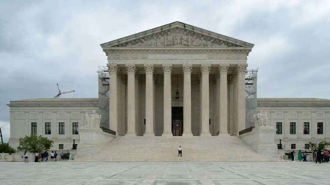 A large building with columns and pillars under a cloudy sky