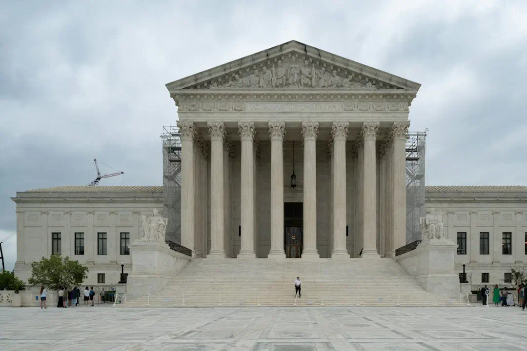 A large building with columns and pillars under a cloudy sky